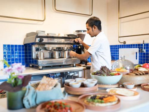 a man standing in a kitchen preparing food at The Project Cafe and Hotel in Aldona