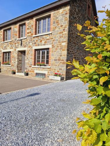 a brick building with windows and a gravel driveway at Chez Camil in La-Roche-en-Ardenne