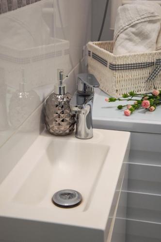 a bathroom sink with a soap dispenser on it at Apartamenty Tercet DUO BIS in Ustka