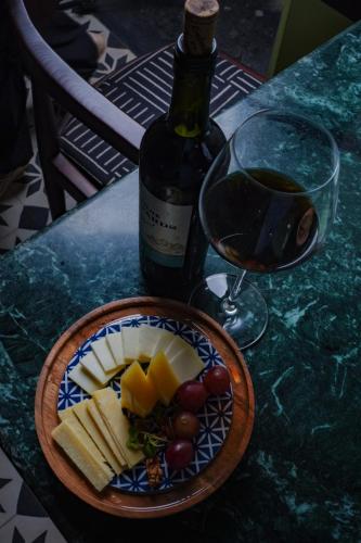 a plate of cheese and grapes next to a bottle of wine at The Project Cafe and Hotel in Aldona