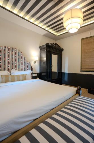 a bedroom with a large white bed and a chandelier at The Project Cafe and Hotel in Aldona