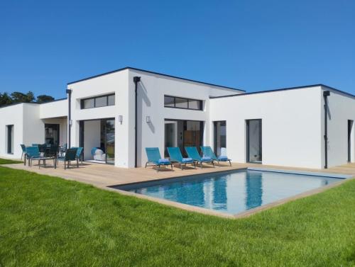 une maison avec une piscine et des chaises bleues dans l'établissement Escapade Marine piscine et spa pour 10, à Carantec