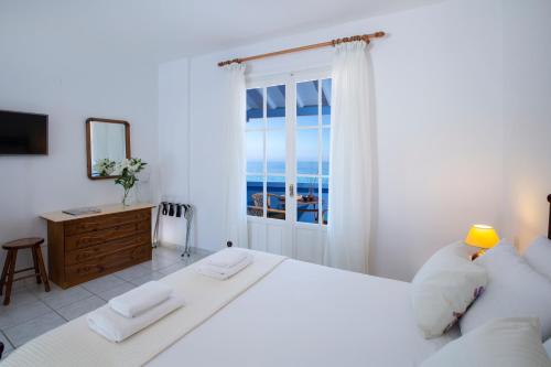 a white bedroom with a large bed and a window at Pantazis Studios in Agios Nikitas in Agios Nikitas