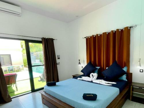 a bedroom with a bed with blue sheets and orange curtains at RESIDENCE SAPHIR in Mahajanga