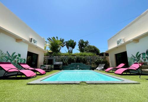 a backyard with a swimming pool and pink chairs at RESIDENCE SAPHIR in Mahajanga