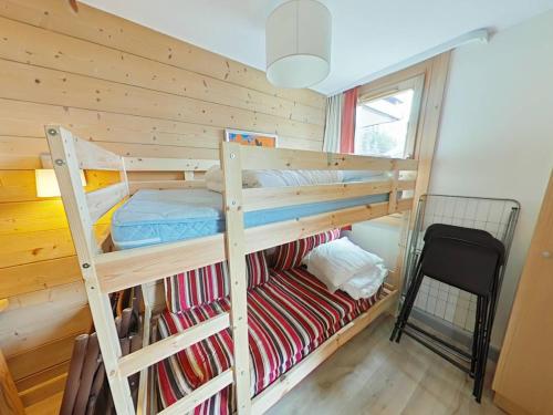 - une chambre avec 2 lits superposés et une chaise dans l'établissement Appartement cosy à La Plagne avec balcon ensoleillé et parking couvert - FR-1-351-250, à La Plagne Tarentaise