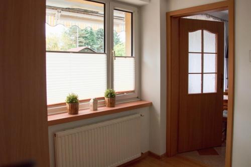 a window with two potted plants on a window sill at Apartamenty Tercet, Apartament Kwartet, Apartament DUO in Ustka