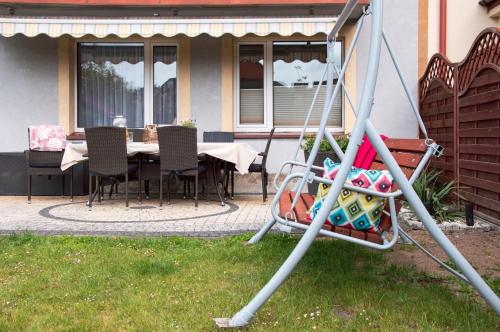 a swing in front of a house with a table and chairs at Apartamenty Tercet, Apartament Kwartet, Apartament DUO in Ustka