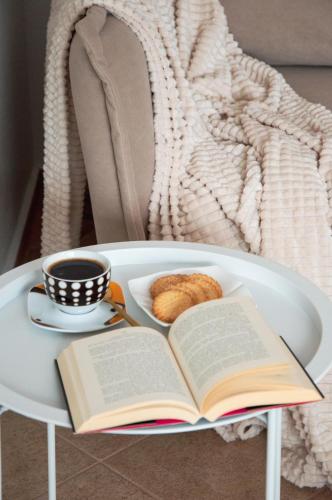 a book and a cup of coffee and a plate of bread at Apartamenty Tercet, Apartament Kwartet, Apartament DUO in Ustka