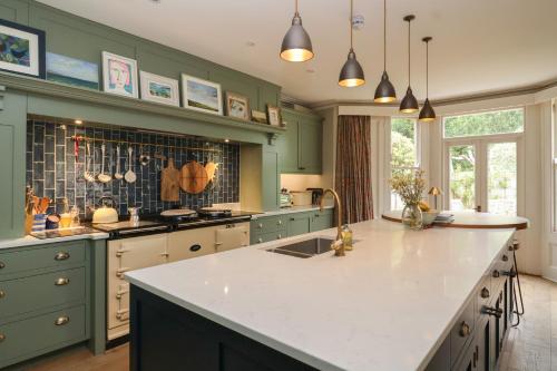 a kitchen with green cabinets and a white counter top at The Old Vicarage in Hinton Saint George
