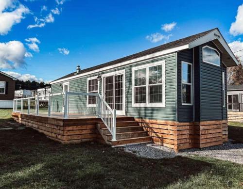 a green house with a porch and stairs at Bobcaygeon Shores Cottage Resort in Kawartha Lakes