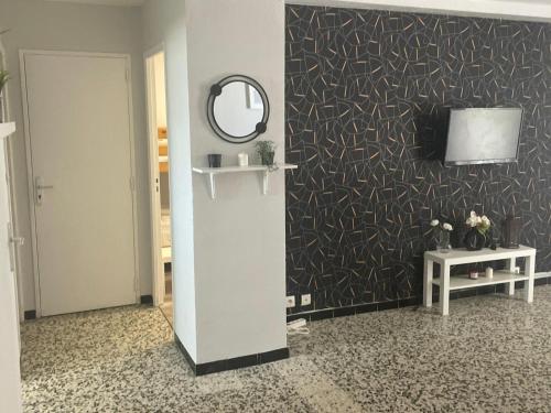 Cette chambre est dotée d'un mur avec un miroir et d'une télévision. dans l'établissement Appartement 2 chambres, à Avignon