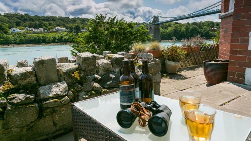 two bottles of beer and glasses on a table at Brig y Don Menai in Menai Bridge