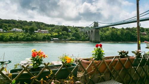 a bridge over a river with two boats with flowers at Brig y Don Menai in Menai Bridge