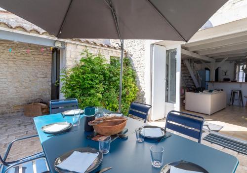 - une table bleue avec des chaises et un parasol sur la terrasse dans l'établissement 990 La Clairière Charm and authenticity, au Bois-Plage-en-Ré