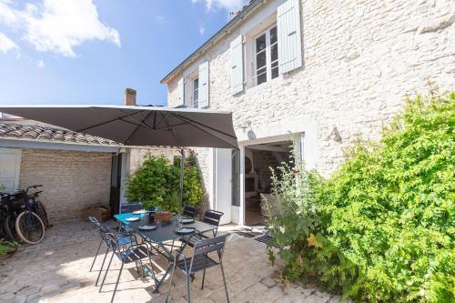 un patio avec une table, des chaises et un parasol dans l'établissement 990 La Clairière Charm and authenticity, au Bois-Plage-en-Ré