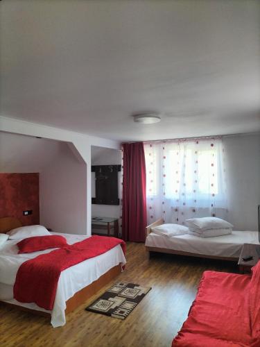 a bedroom with two beds and a red blanket at Nopti de Vara Transfăgărășan in Căpăţîneni-Pămînteni