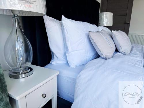 a bed with white pillows and a lamp on a night stand at Central cottage Newcastle in Newcastle