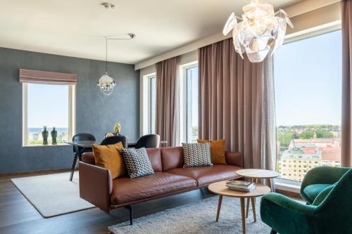 a living room with a brown couch and a table at ProfilHotels Halmstad Plaza in Halmstad