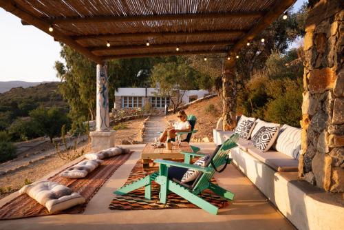a woman sitting on a patio under a wooden pergola at Annas Katikia in Drymonas