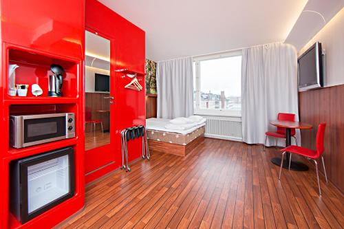 a room with a red wall with a tv in it at Omena Hotel Tampere in Tampere
