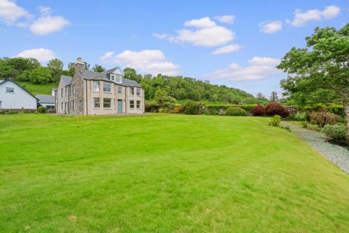 a large grassy yard with a large house at Cuilcheanna House - Onich, Fort William in Onich