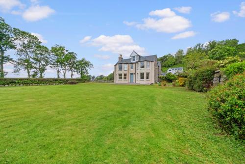 a large grassy yard with a large house at Cuilcheanna House - Onich, Fort William in Onich