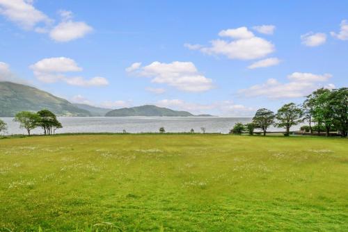 a green field with trees and a large body of water at Cuilcheanna House - Onich, Fort William in Onich