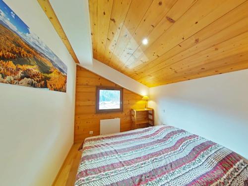 une chambre avec un lit dans une pièce avec des plafonds en bois dans l'établissement Appt au centre avec 2 chambres, balcon, casier à ski et tout confort au Grand-Bornand - FR-1-241-61, au Grand-Bornand