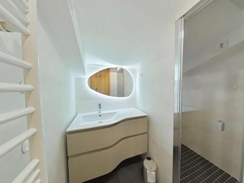 une salle de bain blanche avec un lavabo et un miroir dans l'établissement Appt au centre avec 2 chambres, balcon, casier à ski et tout confort au Grand-Bornand - FR-1-241-61, au Grand-Bornand