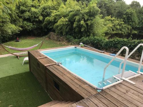 une grande piscine avec une terrasse en bois dans l'établissement au milieu des bois, à Saint-Pons-la-Calm