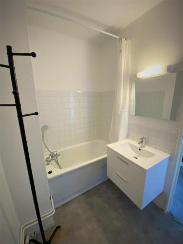 une salle de bain blanche avec une baignoire et un lavabo dans l'établissement Appartement double 23 à Limoges, à Limoges