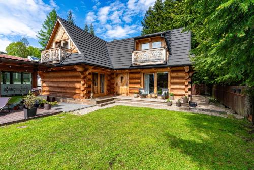 a log home with a lawn in front of it at Willa Baciarka-basen, sauny i jacuzzi in Kościelisko