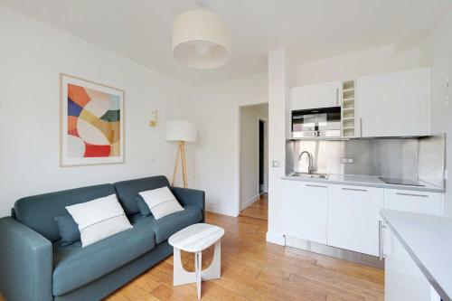 un salon avec un canapé bleu et une cuisine dans l'établissement Cosy Apartment -1BR-2P- Suresnes, à Suresnes