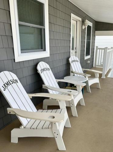 four white chairs sitting on the porch of a house at Luxury Beachfront penthouse with rooftop ocean views off private balcony in Seaside Heights