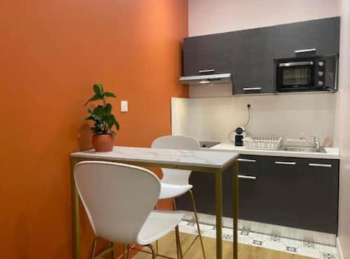 une cuisine avec trois chaises blanches et une table dans l'établissement Charmant studio équipé, à Oullins