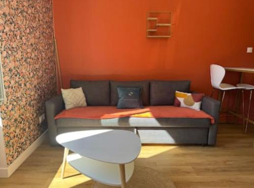 - un canapé dans le salon avec un mur orange dans l'établissement Charmant studio équipé, à Oullins