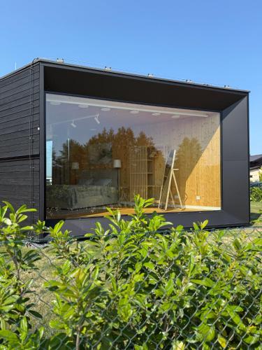 a black house with a large window behind a bush at Beach Villa v Penati Golf Resort in Šajdíkove Humence