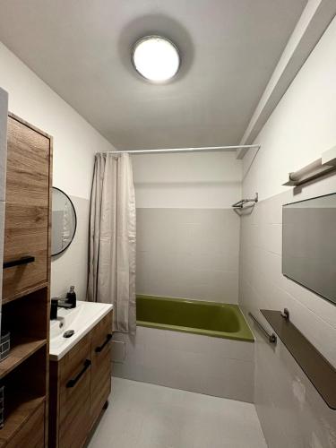 La salle de bains est pourvue d'une baignoire verte et d'un lavabo. dans l'établissement Appartement T2, à Port-la-Nouvelle
