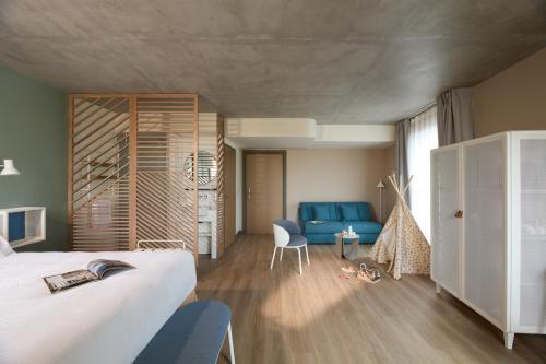 a bedroom with a bed and a blue chair at OKKO Hotels Troyes Centre in Troyes