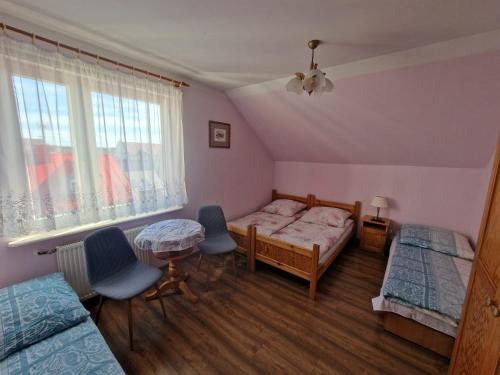 a bedroom with two beds and a table and two chairs at Pensjonat Elżbieta in Łeba