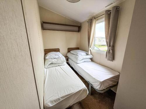 twee bedden in een kleine kamer met een raam bij Caravan In Scratby, Norfolk Ref 50071D in Great Yarmouth