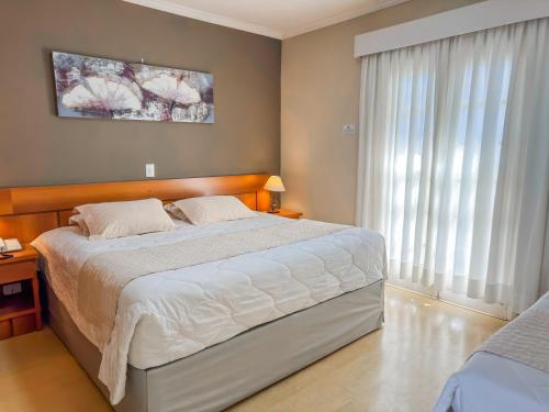 a bedroom with a large bed and a large window at Pousada Nacional Inn Campos do Jordão in Campos do Jordão