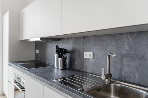 a kitchen with a stainless steel sink and white cabinets at EXQUIS Design 4-Zimmer ART-DECÓ I Balcony I Family-friendly I Parking I Home Office in Böblingen