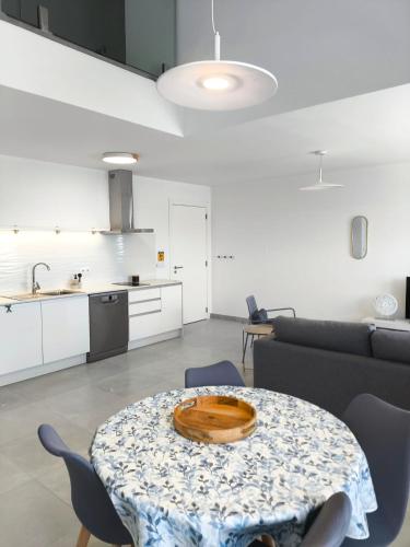 a living room with a table and a kitchen at Waves and Trails in Porto Covo