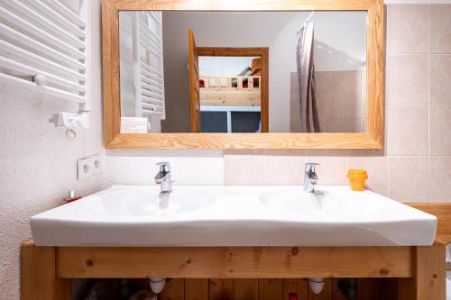 ein Badezimmer mit einem weißen Waschbecken und einem Spiegel in der Unterkunft Les Arolles n°G54 in Valloire