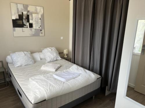a bed with white sheets and pillows in a bedroom at Résidence Dalma appartement 7 in Cazaubon