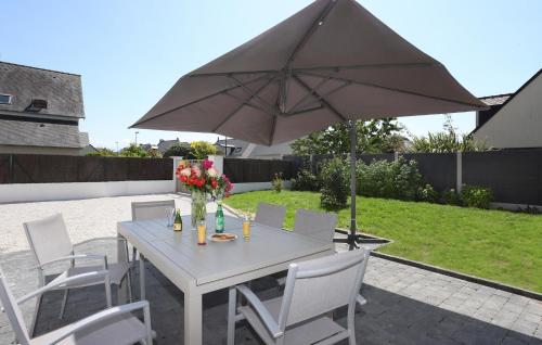 une table et des chaises blanches avec un parasol dans l'établissement Lovely Home In Saint-Méloir-Des-Ondes, à Saint-Méloir-des-Ondes
