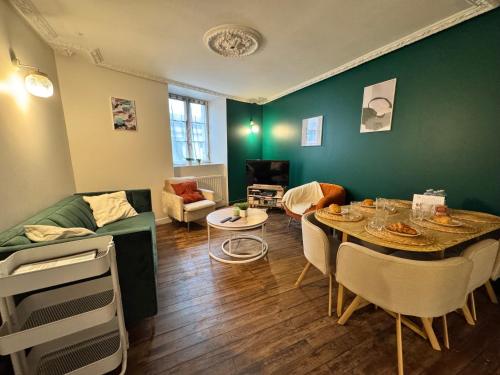 a living room with a table and a green wall at La Maison D'Oscar in Parthenay