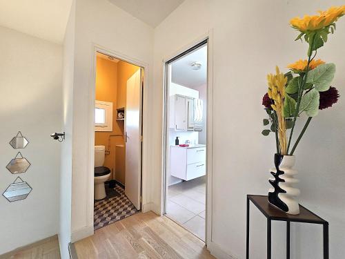 un couloir avec des toilettes et un vase de fleurs sur une table dans l'établissement Belle villa au bord du canal - Piscine, jardin et bois -14 personnes - 6 chambres - 5 minutes de la gare - Terrasses et pergola - Parking gratuit, à Montauban